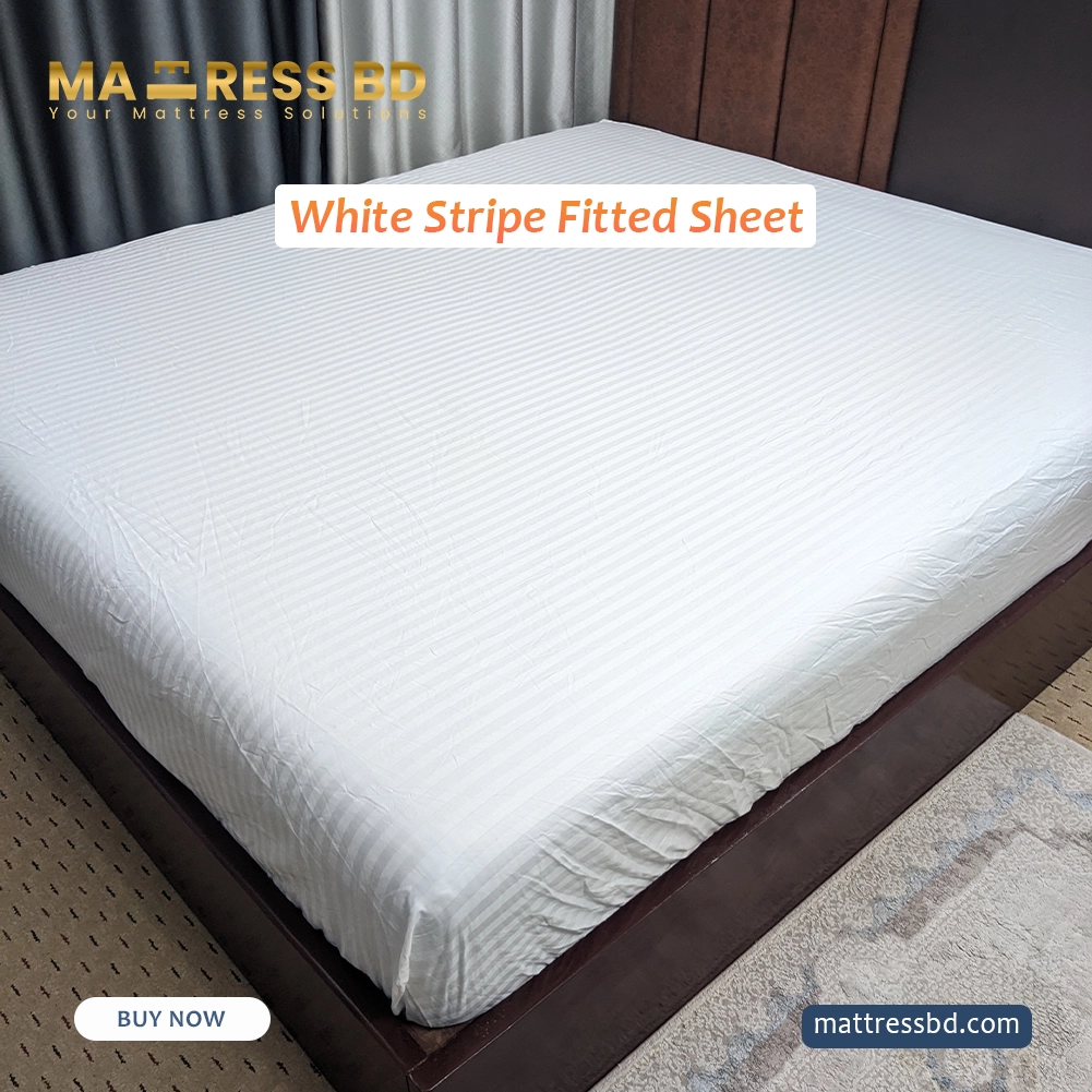 Detail view of the deep pocket corner and elastic hem of luxury white striped fitted sheet being tucked under a thick mattress.